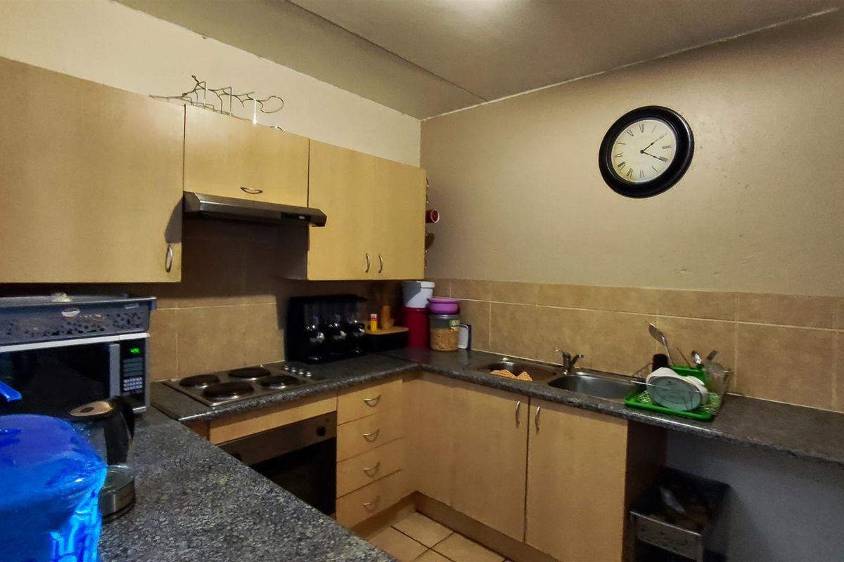 A functional kitchen featuring laminate cabinetry, stone-look laminate countertops, a built-in oven with electric hob, and a tiled backsplash.
