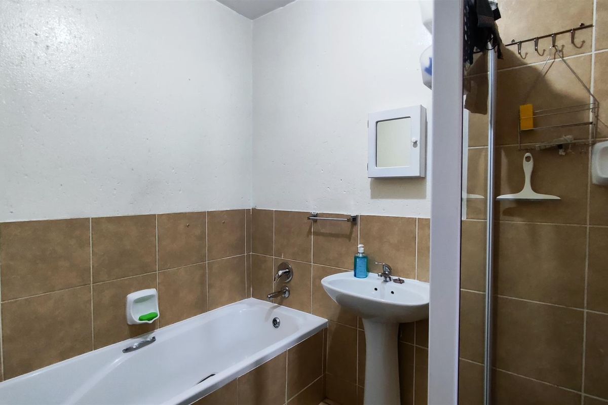 A functional bathroom featuring a pedestal basin, bathtub, and separate shower enclosure with tiled wall finishes.