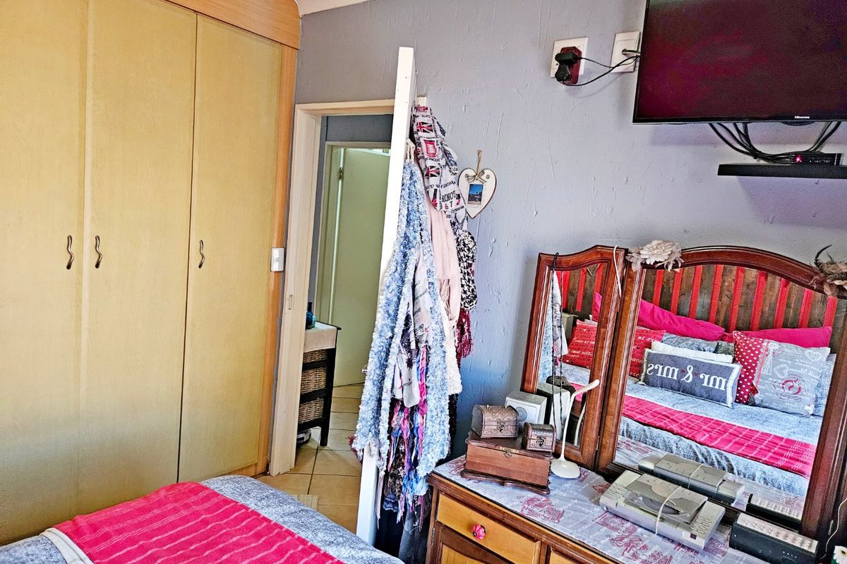 A bedroom featuring built-in cupboards and visible wall plaster cracking, requiring cosmetic attention to improve the overall finish.