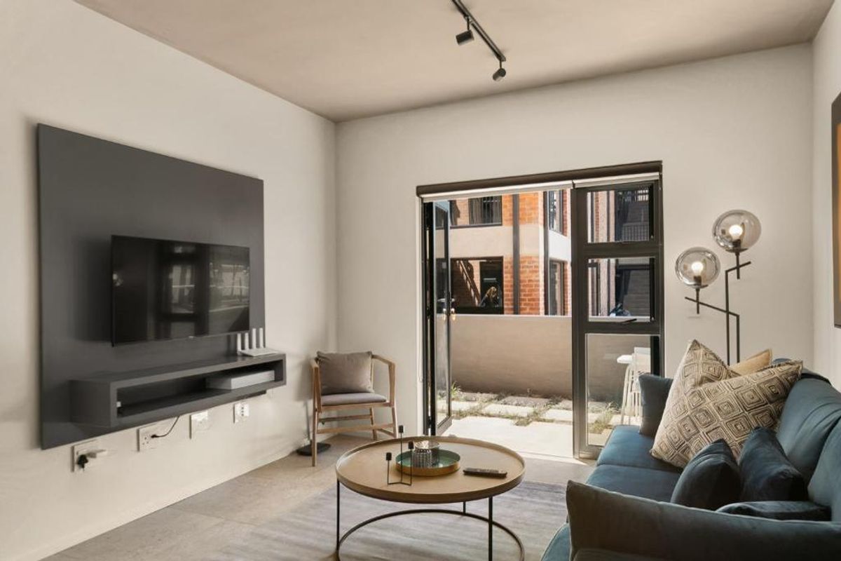 Modern living room featuring a built-in media console, sleek track lighting, and large sliding glass doors providing seamless access to the outdoor patio area.