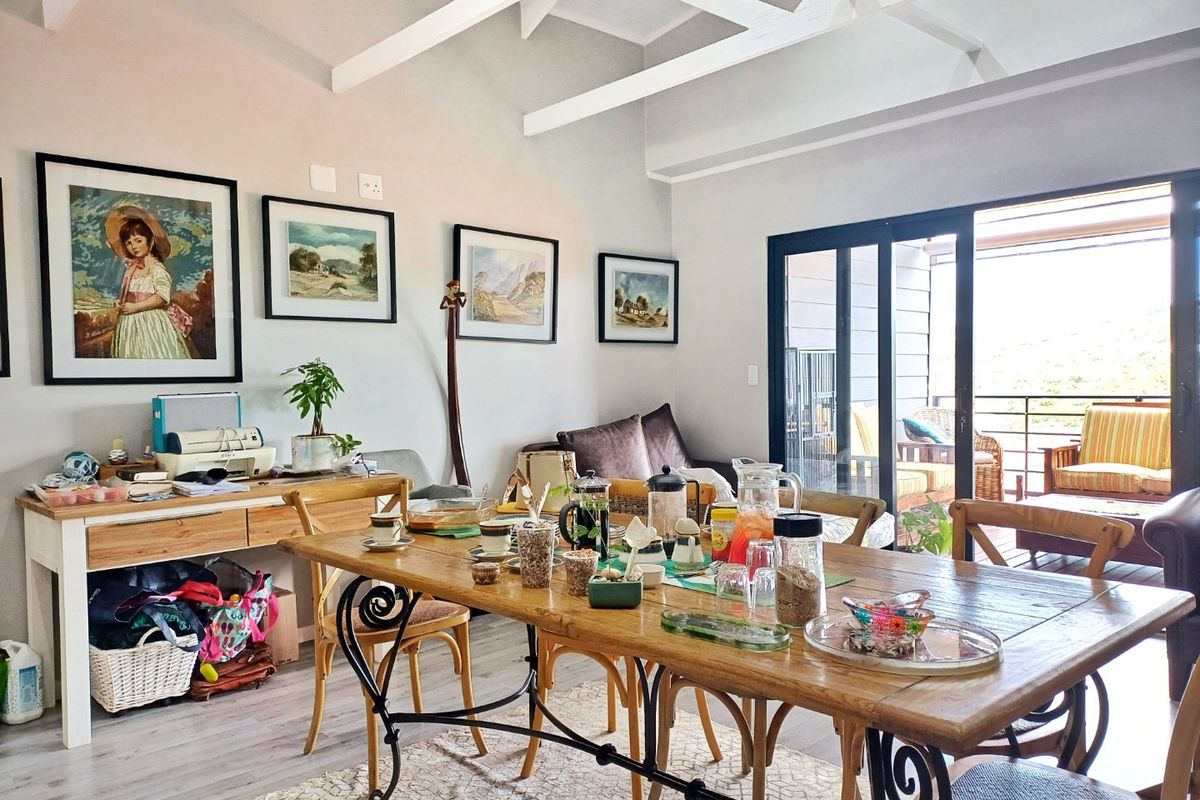 Bright living area featuring exposed white timber ceiling beams, laminate flooring, and large sliding glass doors providing seamless access to the outdoor patio.