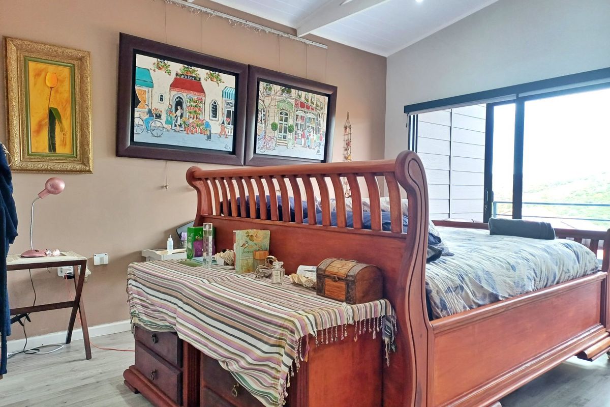 Spacious bedroom featuring vaulted ceilings, laminate flooring, and a large sliding glass door providing natural light and access to the outdoors.
