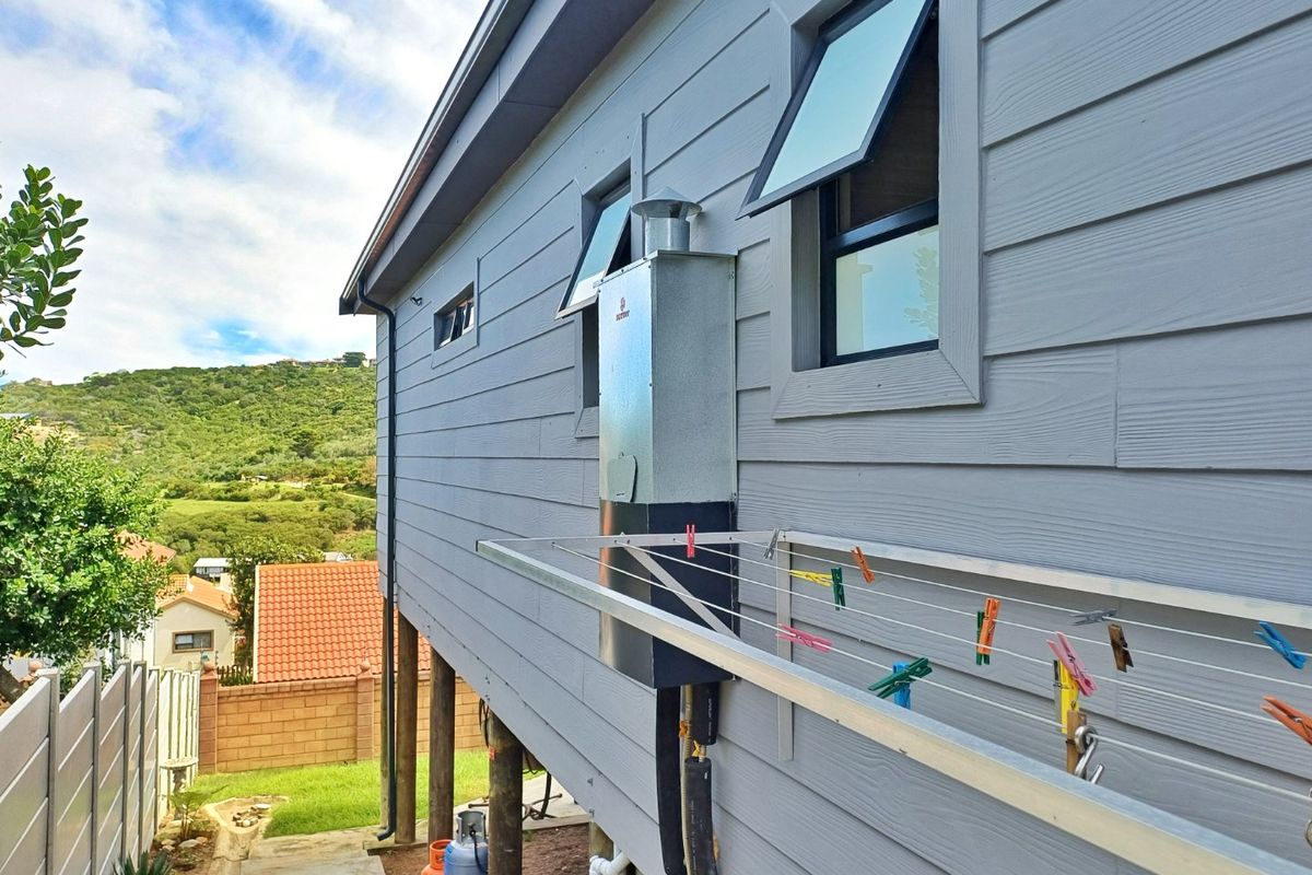 Rear exterior view of the apartment featuring weatherboard cladding, an installed gas geyser, and elevated structural support posts.