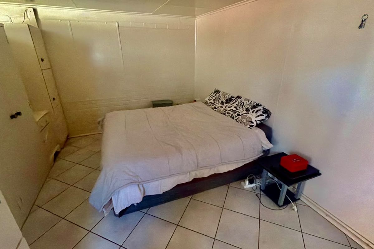 A bedroom featuring ceramic floor tiles and a built-in wardrobe, requiring cosmetic updates to improve the overall finish and aesthetic appeal.