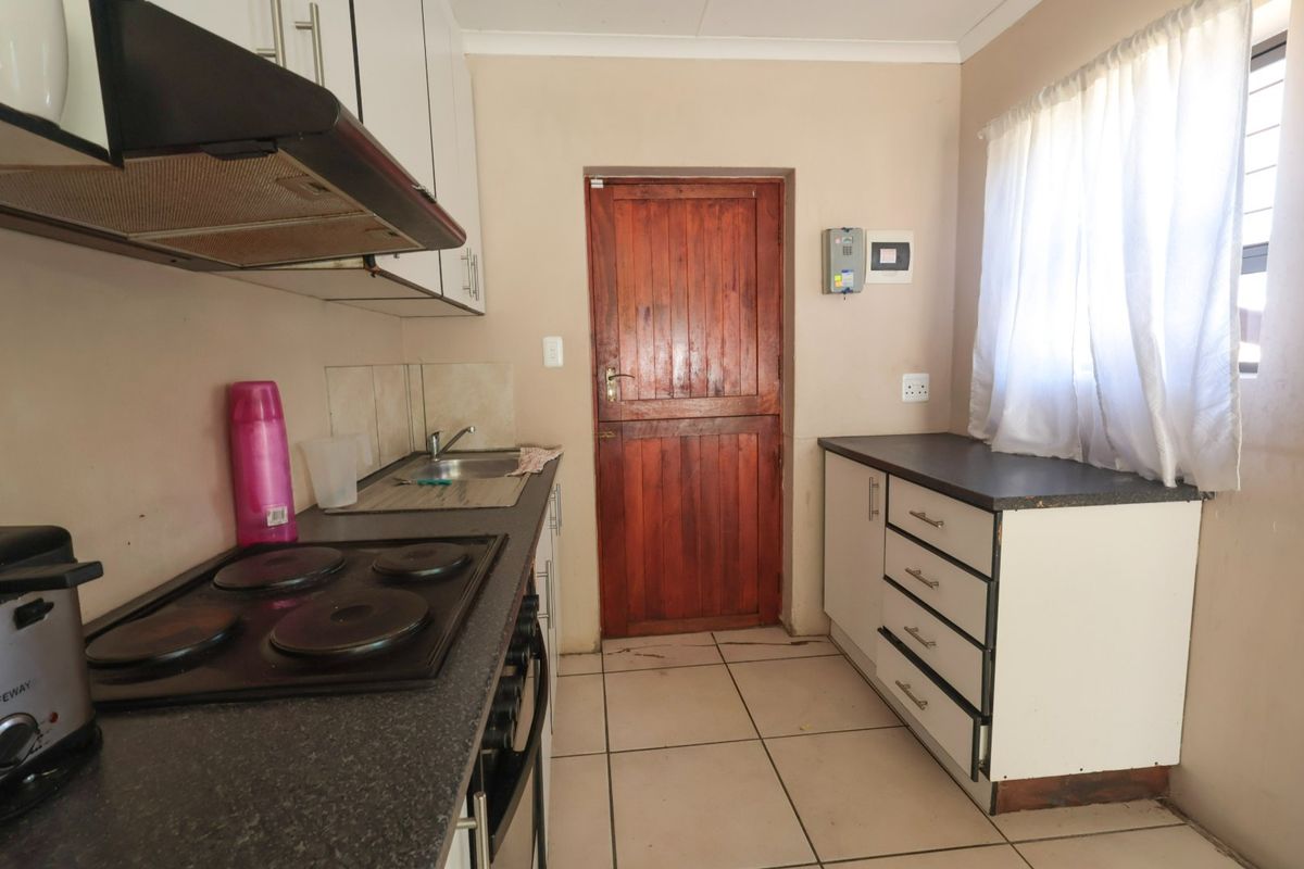 Functional kitchen featuring built-in cabinetry, laminate countertops, an electric hob with extractor fan, and tiled flooring with direct exterior access.
