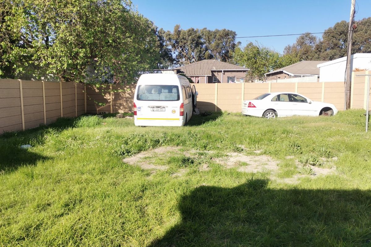 A spacious rear garden area enclosed by a precast concrete boundary wall, featuring an expansive lawn area.