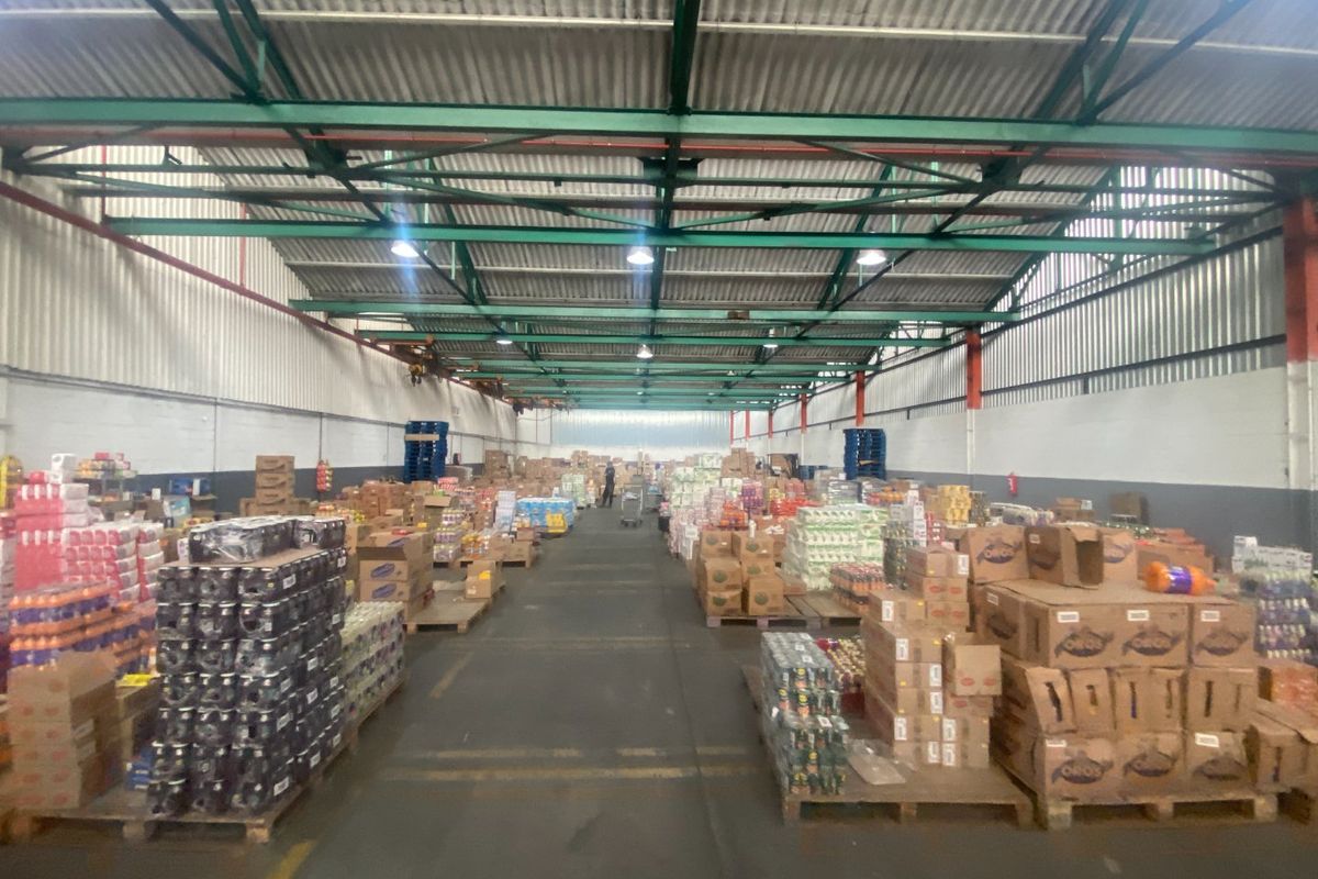 Spacious industrial warehouse featuring high-clearance ceilings with exposed steel trusses, concrete flooring, and functional high-bay lighting, suitable for storage or distribution operations.