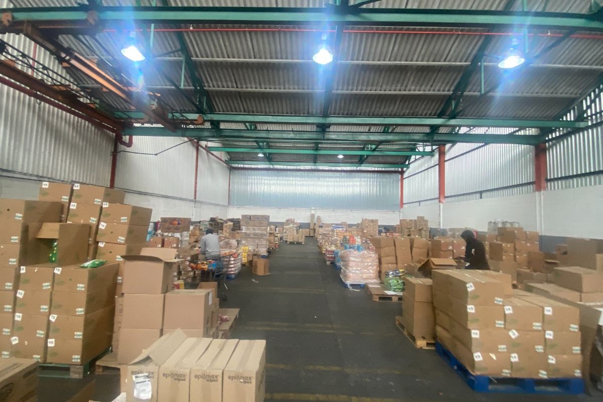 Spacious industrial warehouse facility featuring high-bay lighting, exposed steel roof trusses, and durable concrete flooring, suitable for storage or distribution operations.