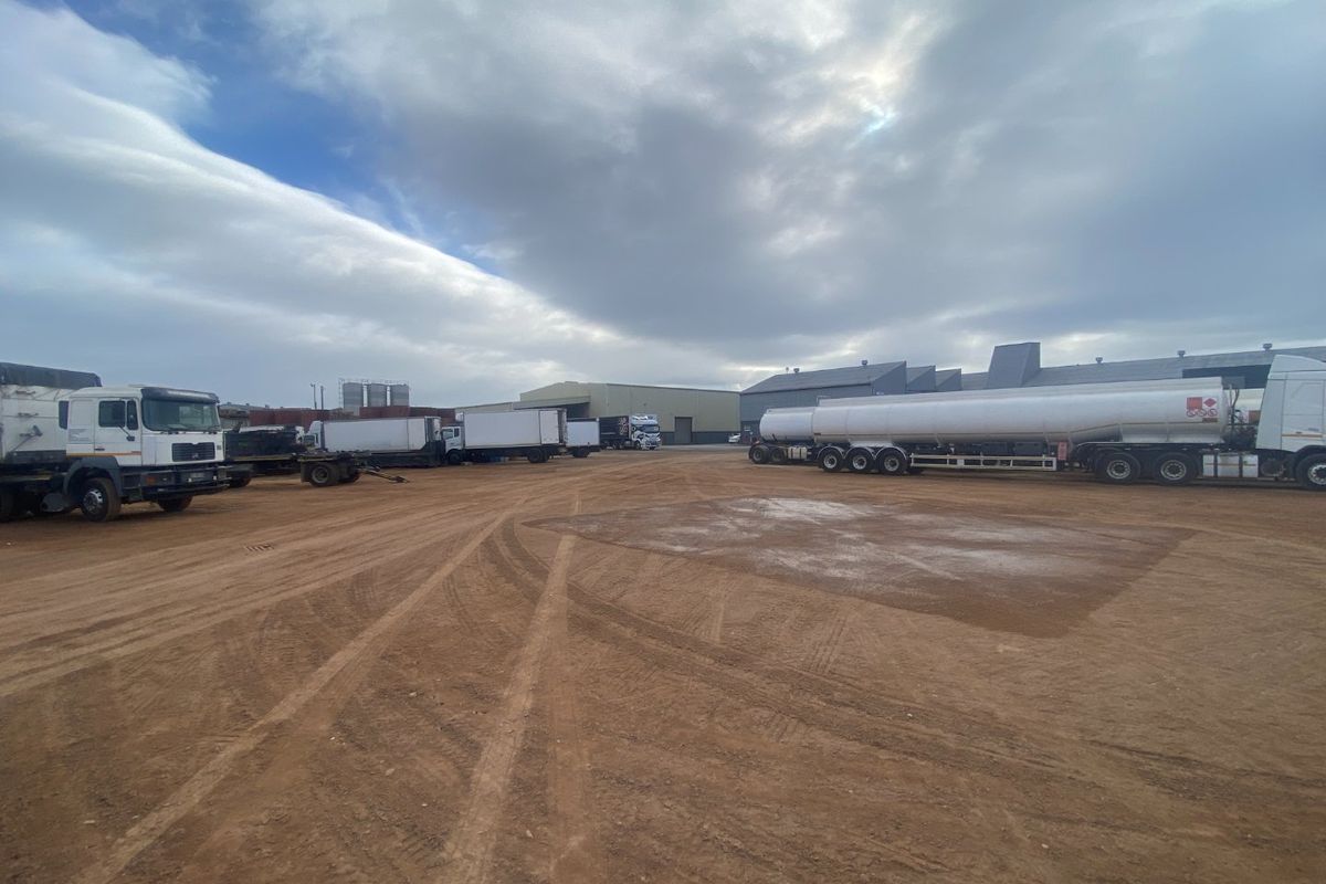 Expansive industrial yard area featuring large warehouse structures and significant open space for vehicle maneuvering and storage.