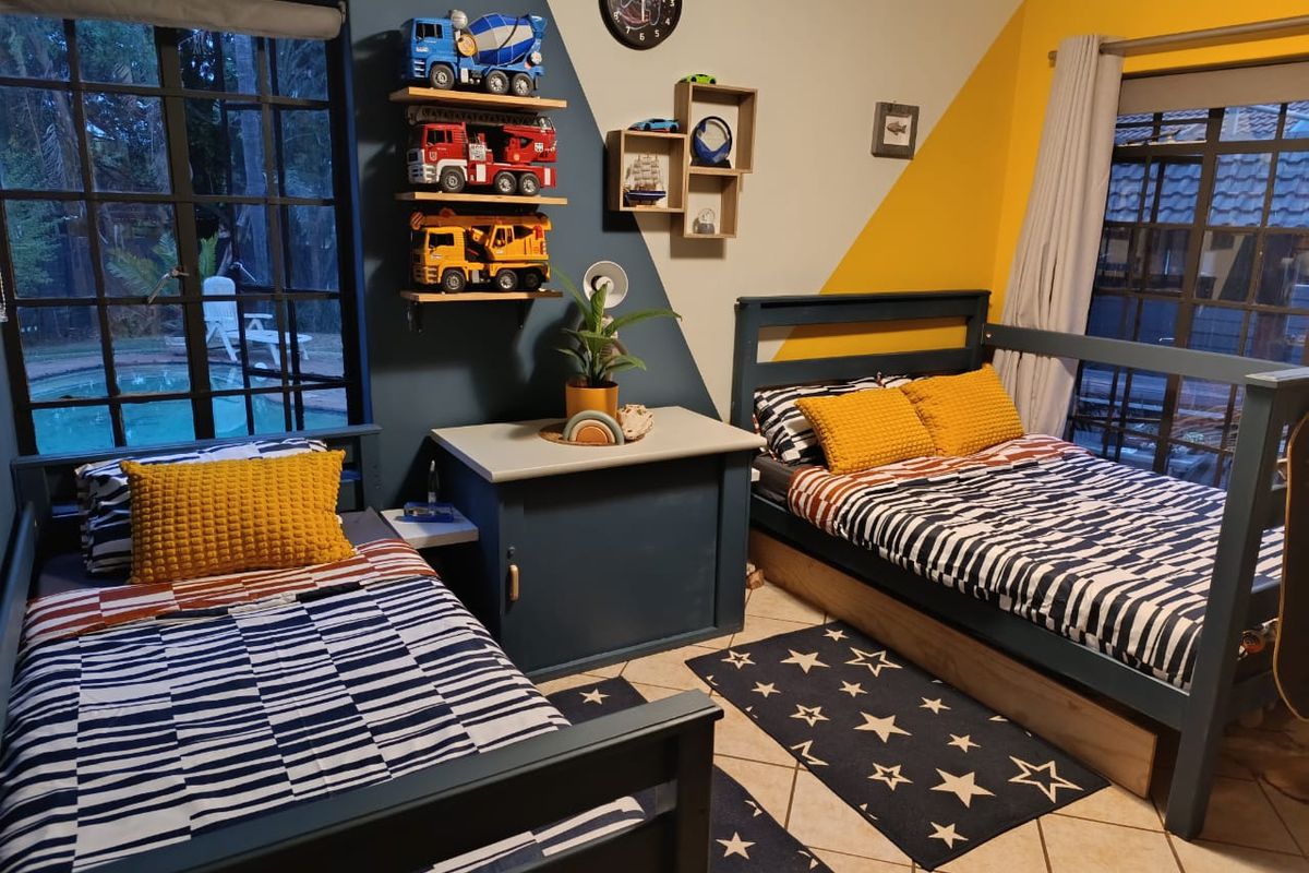 A bright, multi-colored bedroom featuring tiled flooring, large windows, and a sliding glass door providing views of the outdoor pool area.