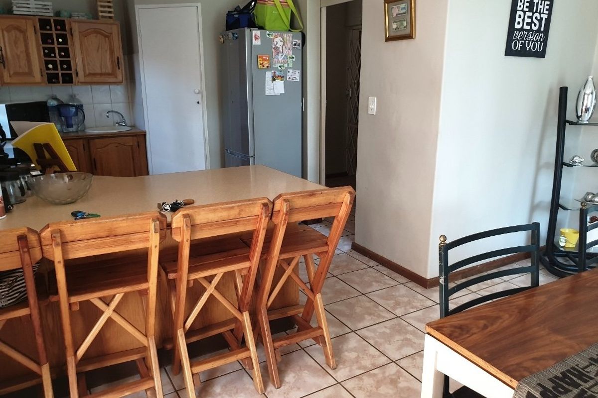 A functional kitchen area featuring wooden cabinetry, a breakfast bar with seating, and tiled flooring, offering a practical layout for daily use.