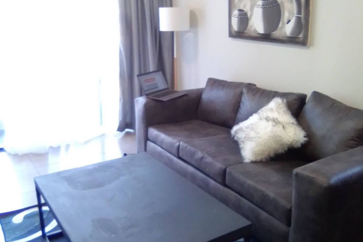 A living room area featuring tiled flooring and a sliding glass door providing natural light.
