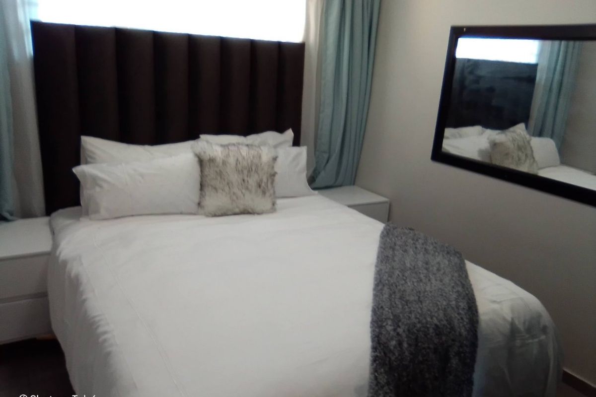 A cozy bedroom featuring a dark upholstered headboard and neutral wall finishes, providing a comfortable and well-maintained sleeping space.