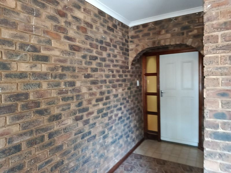 Entrance foyer featuring exposed brick walls, an arched doorway, and a timber-framed glass sidelight, providing a rustic and character-filled welcome to the home.