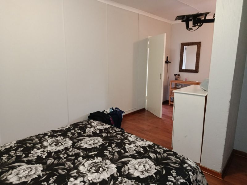 A bedroom featuring laminate flooring and neutral wall finishes, providing a functional space with direct access to an adjoining area.