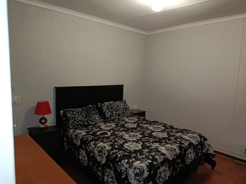 A simple bedroom featuring laminate flooring and neutral wall finishes, providing a functional and comfortable sleeping space.