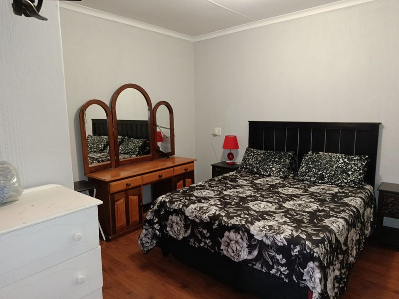 A standard bedroom featuring laminate flooring and neutral wall finishes, providing a functional and comfortable sleeping space.