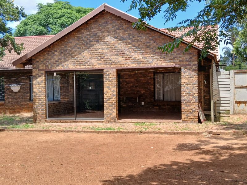 Rear view of a face brick house featuring a covered patio area with sliding glass doors and an expansive garden space.
