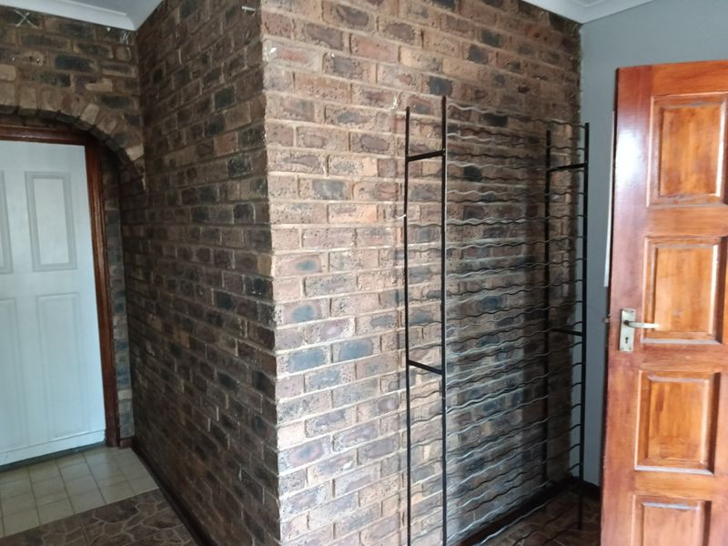 A hallway area featuring an exposed brick feature wall, an arched entryway, and a solid timber door.