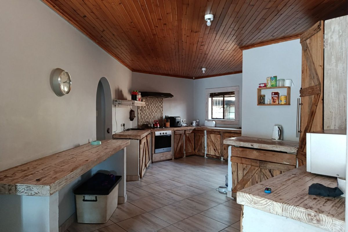 Rustic-style kitchen featuring timber-clad ceilings, custom wooden cabinetry, tiled flooring, and a built-in oven with a tiled backsplash.