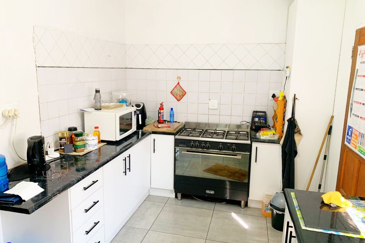A functional kitchen featuring white cabinetry, dark countertops, a gas stove with oven, and tiled backsplash.