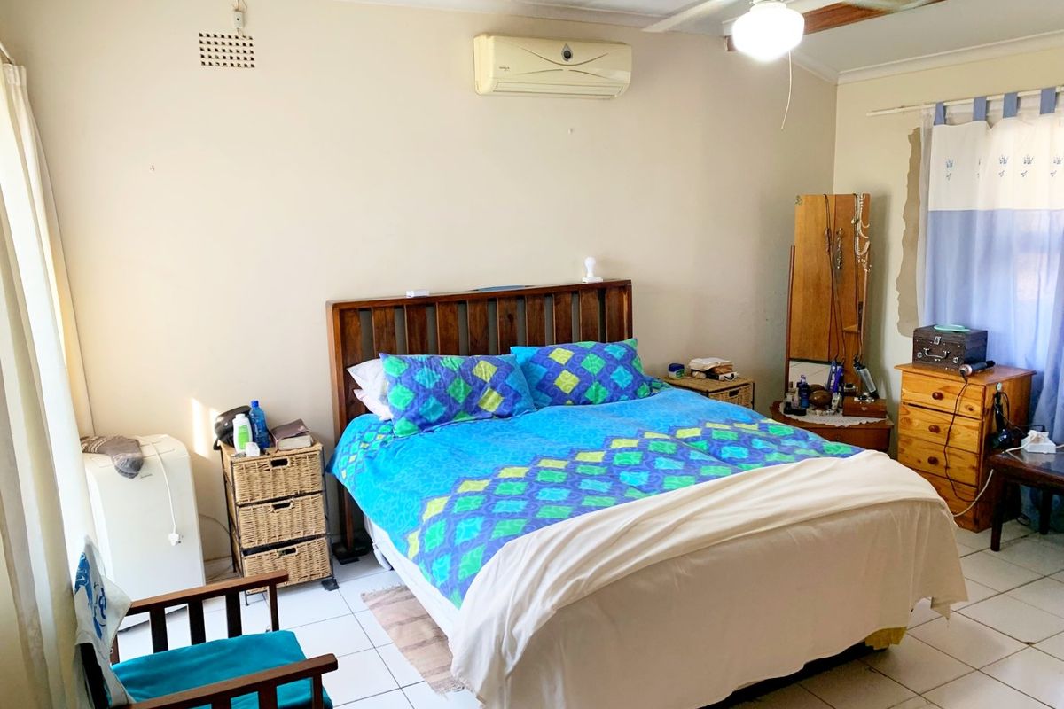 A bedroom featuring tiled flooring, a ceiling fan, and a wall-mounted split-system air conditioner unit.