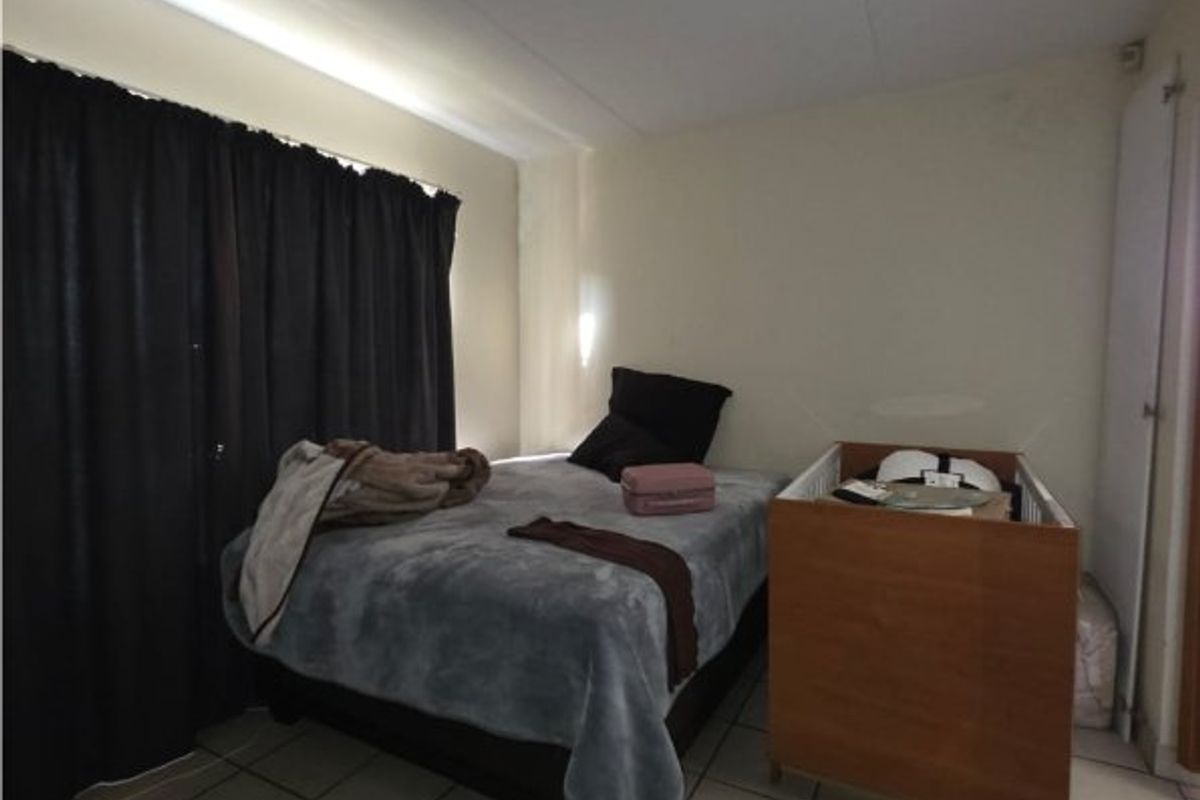 A bedroom featuring tiled flooring and a ceiling-mounted light fixture, providing a functional space with neutral wall finishes.