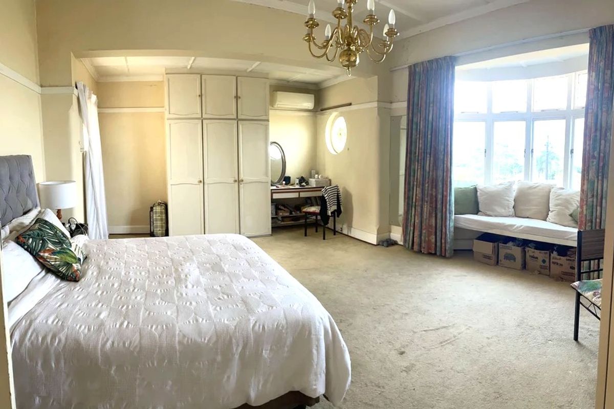 Spacious bedroom featuring built-in wardrobes, a bay window with a built-in window seat, and a split-system air conditioner.