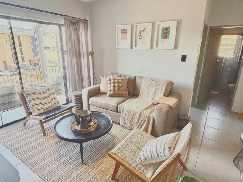 A bright living room featuring tiled flooring and a large sliding glass door that provides access to an outdoor balcony area.