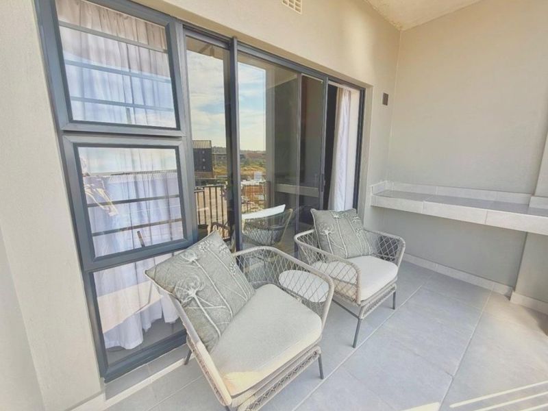 A covered balcony featuring tiled flooring, a built-in counter, and large sliding glass doors providing access to the interior living space.