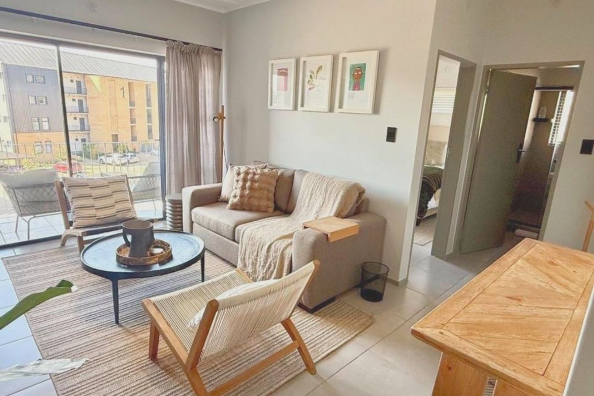 A bright and inviting living room featuring tiled flooring and a large sliding glass door that provides access to a private balcony.