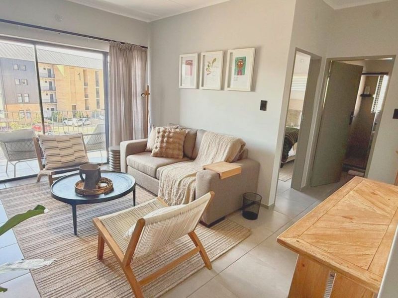 A bright and inviting living room featuring tiled flooring and a large sliding glass door that provides access to a private balcony.