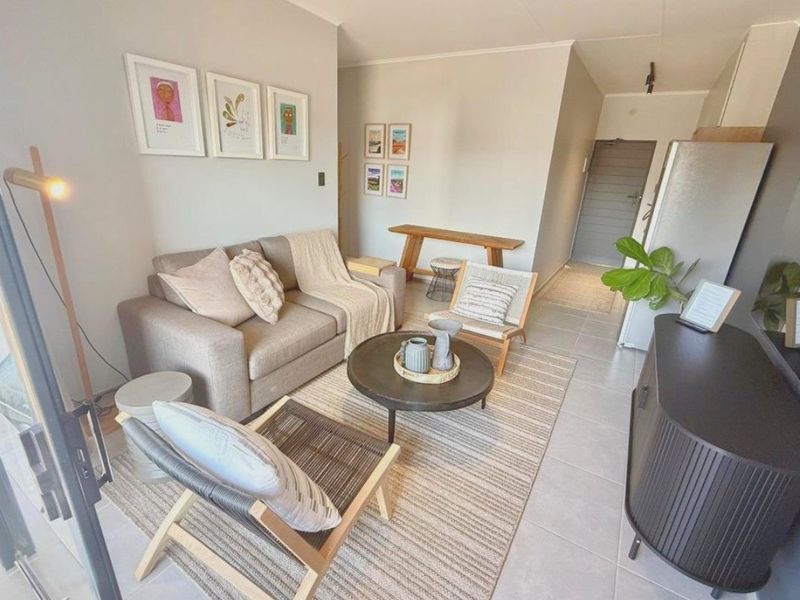 An open-plan living area featuring neutral wall tones and tiled flooring, providing a functional and well-lit space for relaxation and daily living.