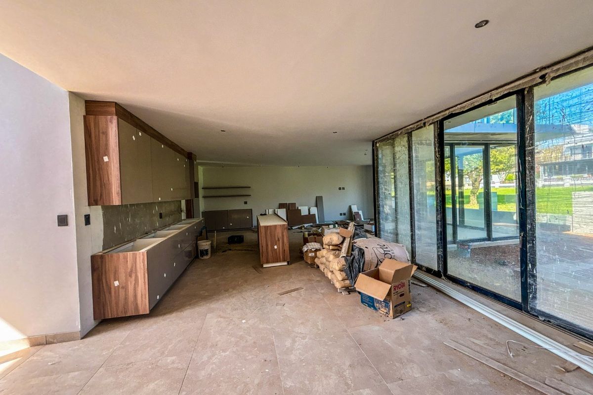 An unfinished kitchen space featuring modern cabinetry, large sliding glass doors, and tiled flooring, currently undergoing renovation and awaiting final installation.