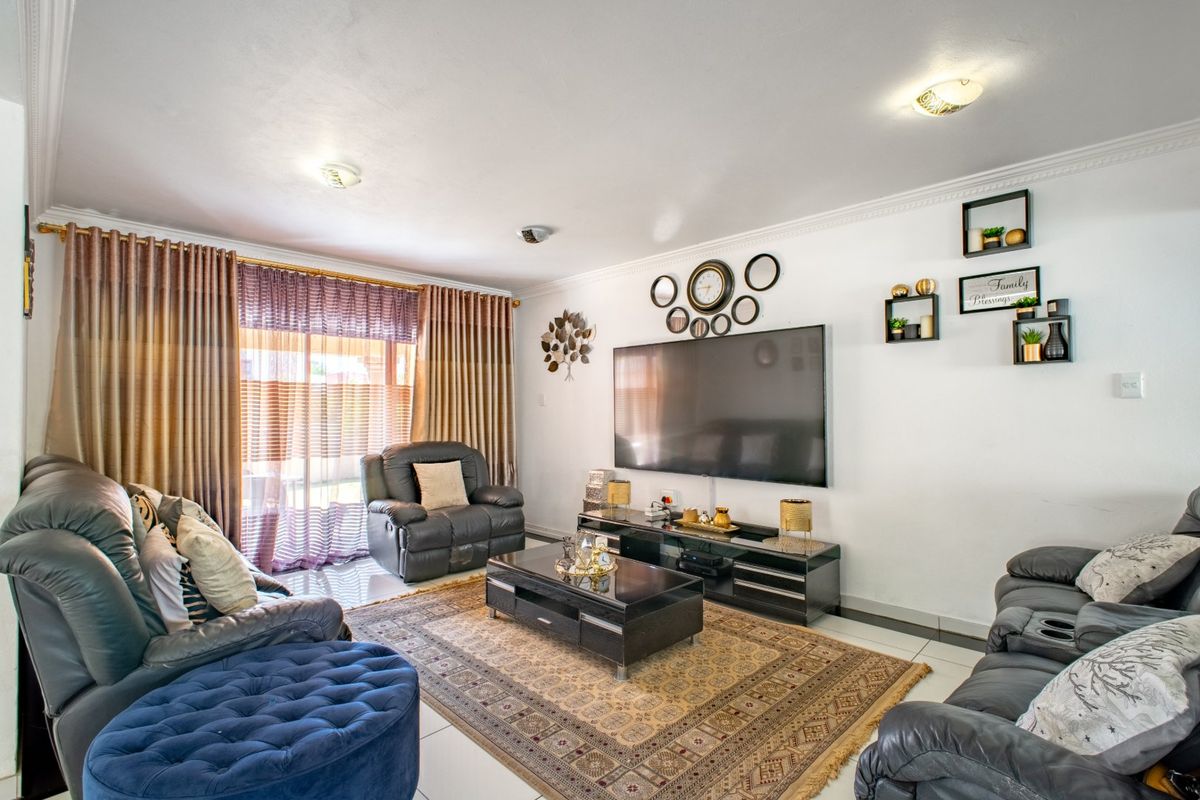 A well-maintained living room featuring tiled flooring, recessed ceiling lighting, and decorative coved cornicing, providing a comfortable and functional space.