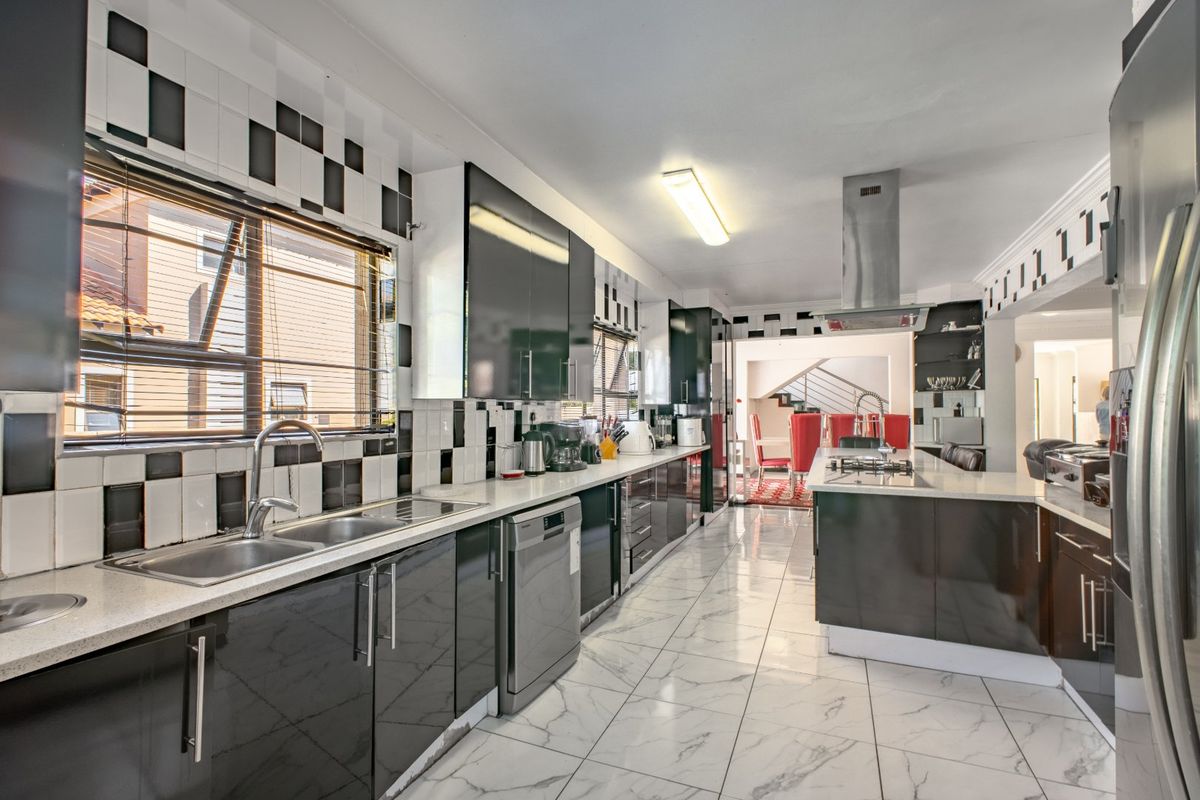 Modern kitchen featuring high-gloss cabinetry, stone countertops, marble-look floor tiles, and integrated appliances, with a functional layout and contemporary tiled splashback.