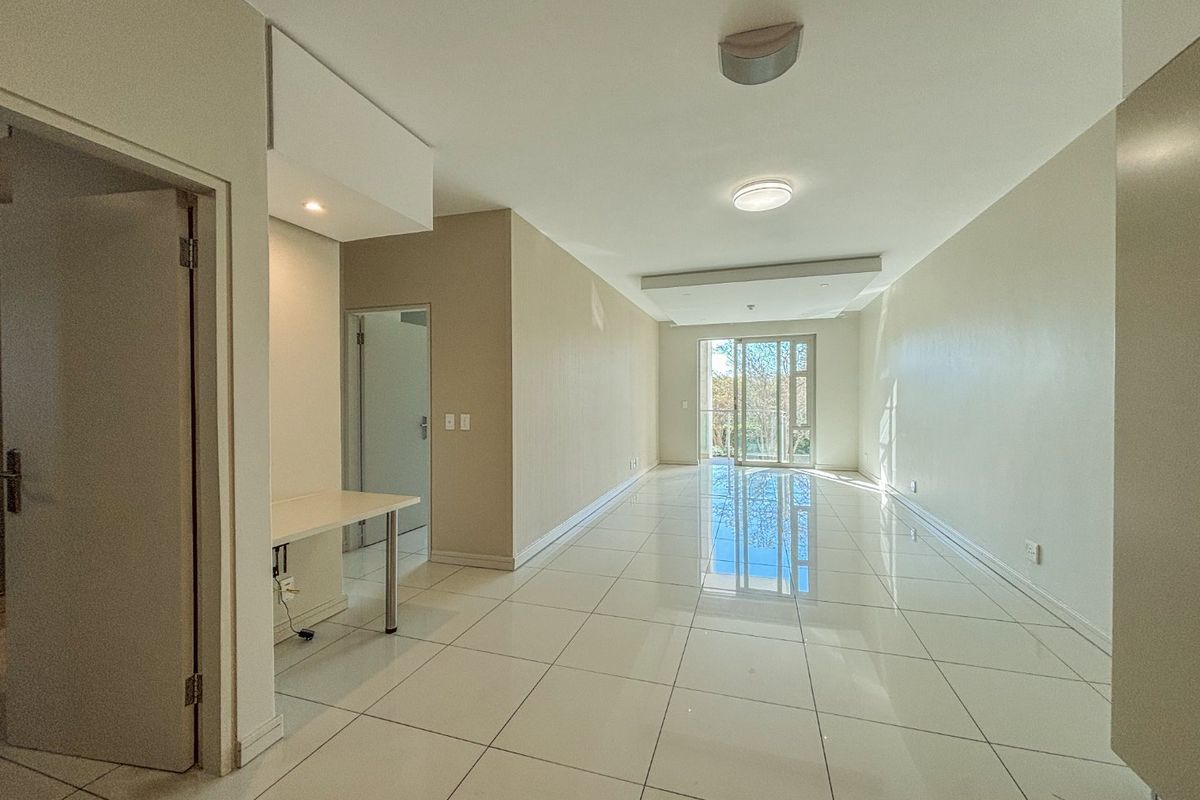 A bright, spacious, and empty living area featuring polished tiled flooring, a modern recessed ceiling design, and a sliding glass door leading outdoors.