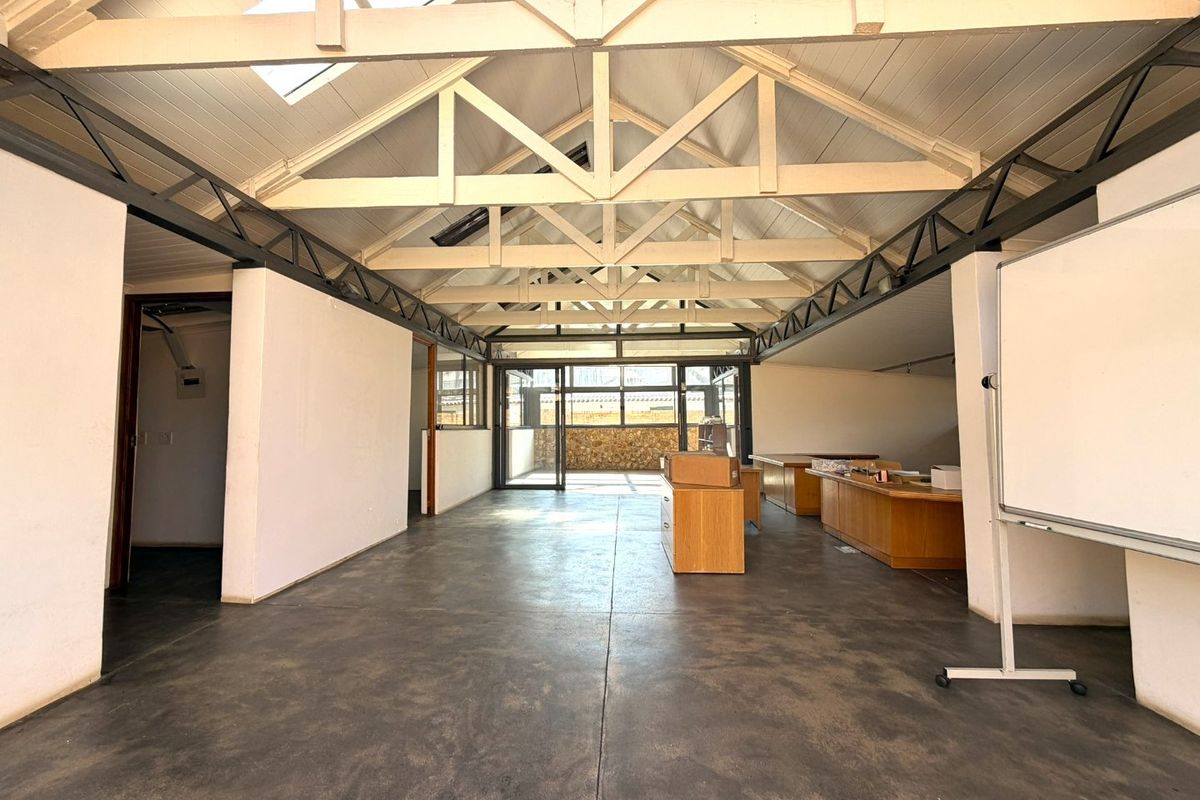 Spacious open-plan area featuring high vaulted ceilings with exposed timber trusses, skylights, and polished concrete flooring, offering versatile potential for various uses.