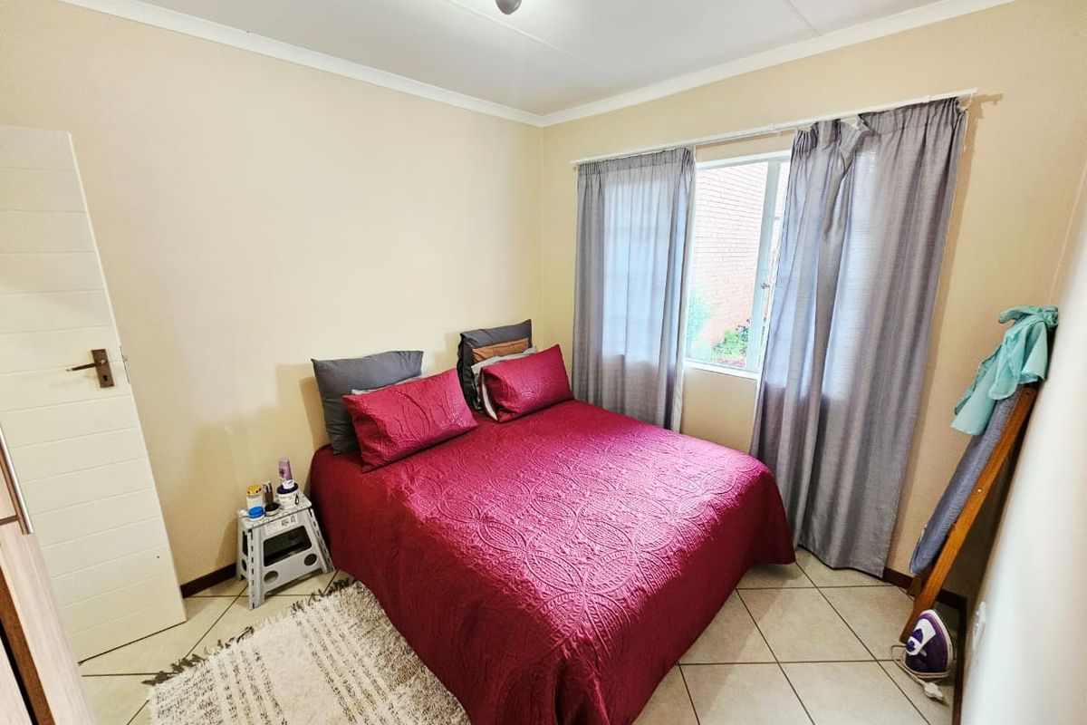 A functional bedroom featuring tiled flooring, neutral wall finishes, and a window with curtain treatments.