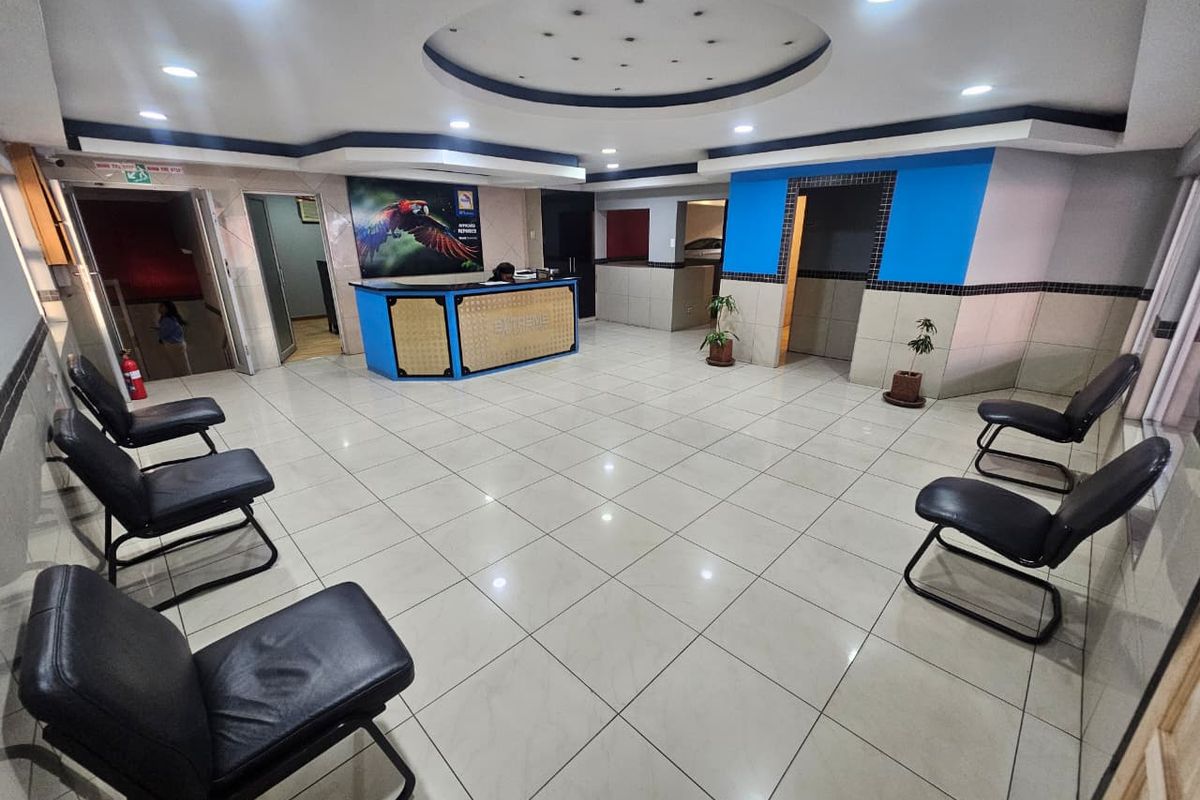A commercial reception area featuring tiled flooring, recessed ceiling lighting, and a built-in reception desk.
