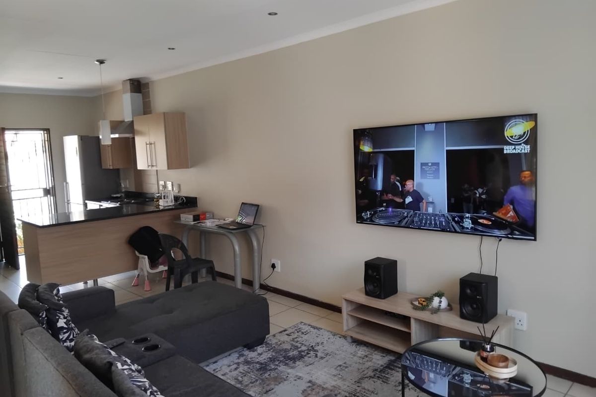 Open-plan living area featuring a modern kitchen with granite countertops and integrated cabinetry, flowing into a comfortable lounge space with tiled flooring.