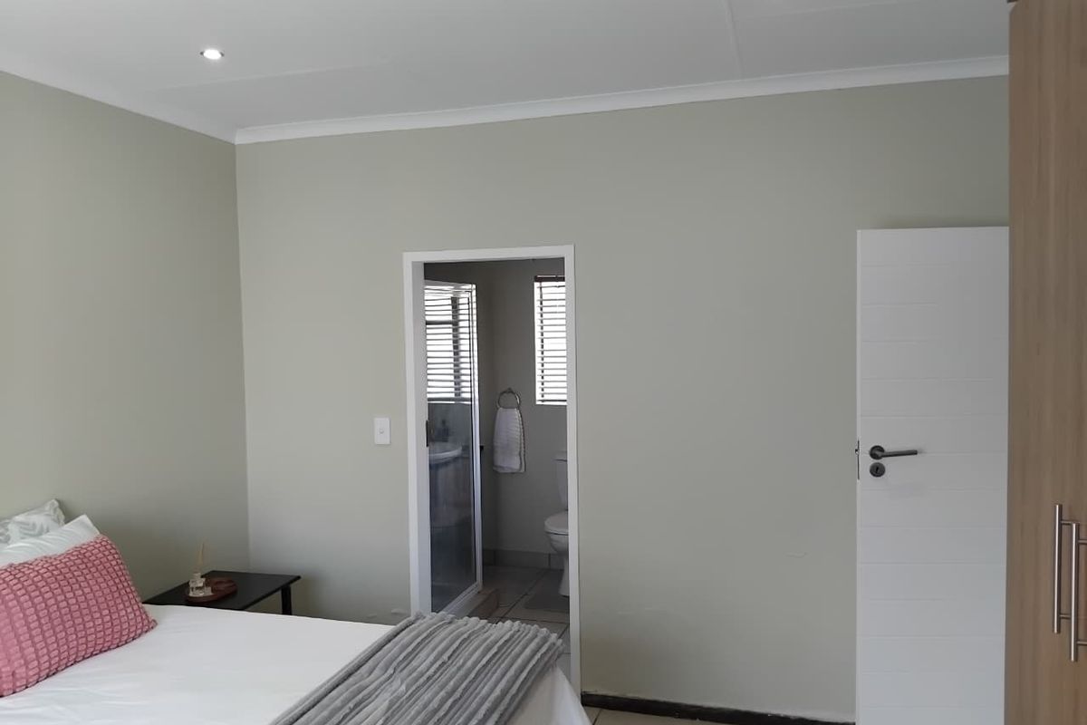 A well-maintained bedroom featuring neutral walls, recessed lighting, tiled flooring, and direct access to an en-suite bathroom.