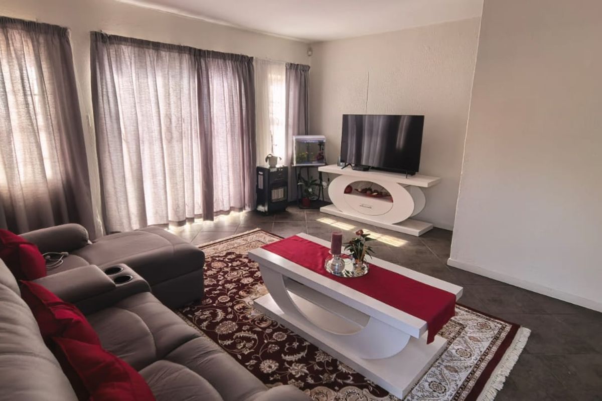 A comfortable living room featuring tiled flooring and large sliding glass doors that provide natural light and access to the outdoor area.