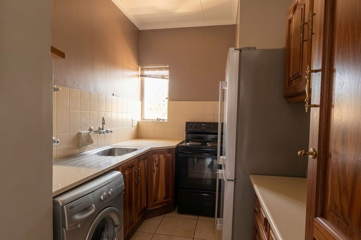 Compact kitchen featuring timber cabinetry, laminate countertops, tiled splashback, and a freestanding oven, offering a functional layout with space for laundry appliances.