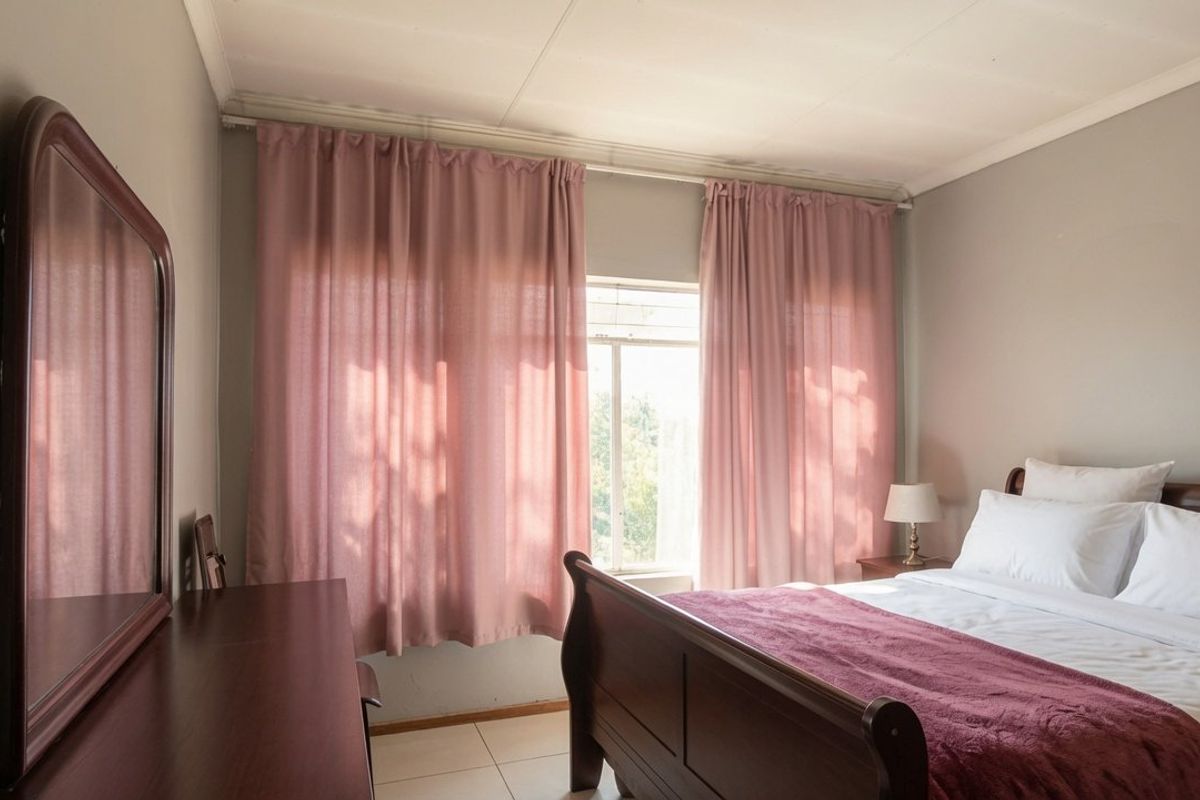A well-lit bedroom featuring tiled flooring and large windows with curtain tracks, offering a neutral base for personalization.