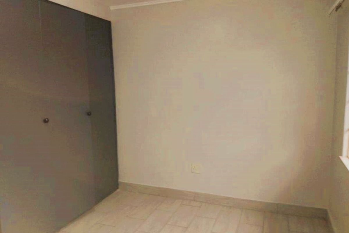 A vacant bedroom featuring neutral wall finishes, tiled flooring, and built-in cupboards providing ample storage space.