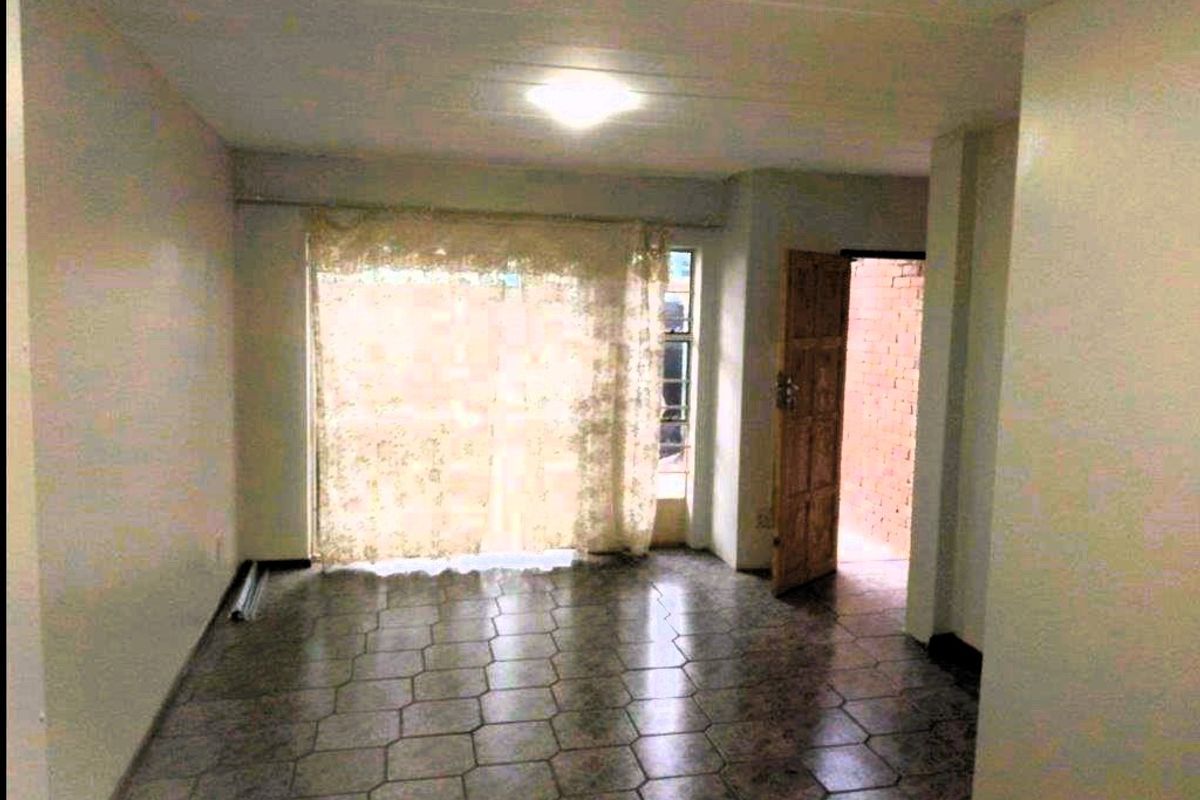 An empty living room featuring tiled flooring and a sliding glass door leading to an outdoor area.