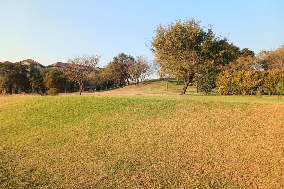 A well-maintained, expansive grassy garden area featuring mature trees and established hedging, providing a pleasant outdoor space.