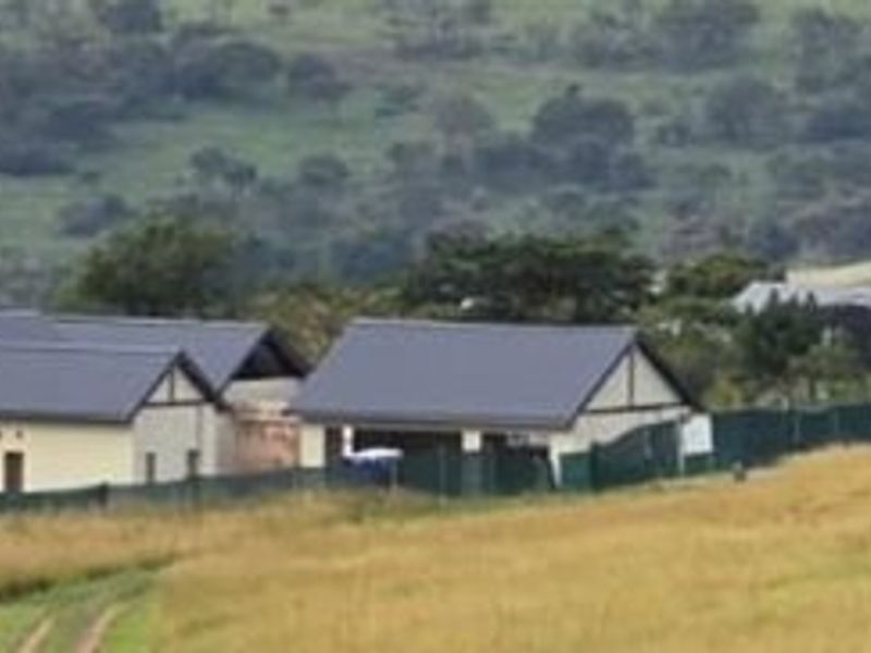 An aerial view of a residential property featuring multiple structures with pitched roofs, set within a rural landscape.