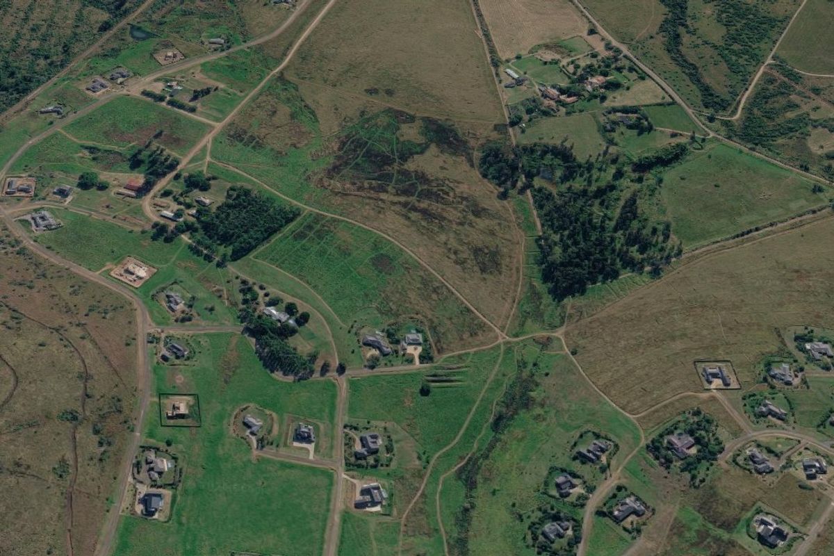 An aerial view of a residential development area featuring multiple plots of vacant land and established rural road infrastructure.
